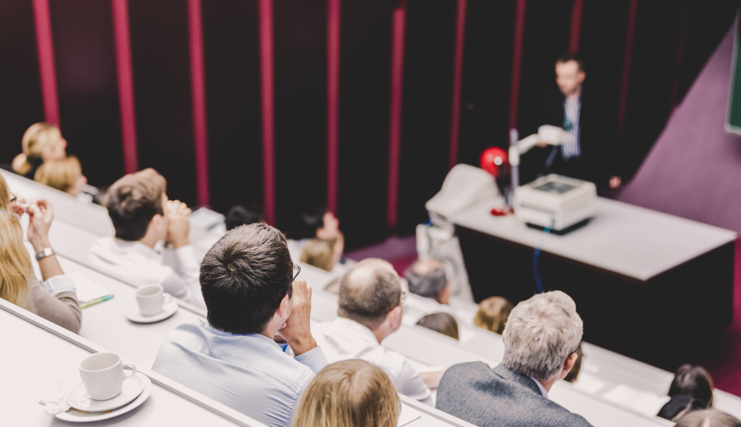Lecturer at university. Medical expert giving a talk as an faculty professor. Participants listening to lecture and making notes.